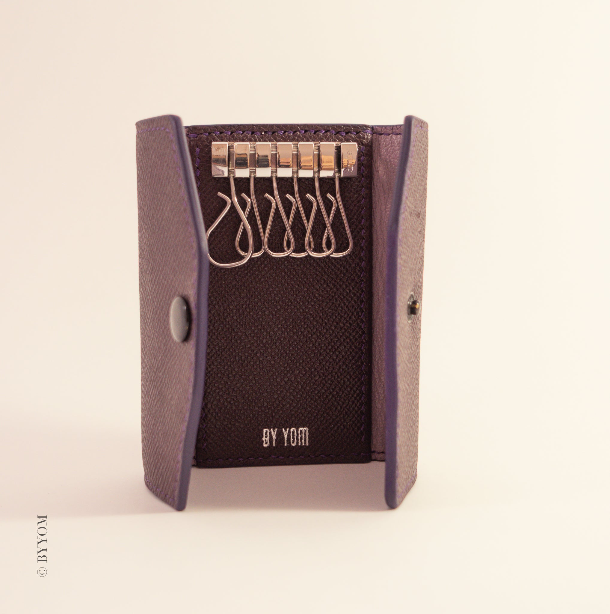 Key holder with hooks on a beige background, branded 'BY YOM'.